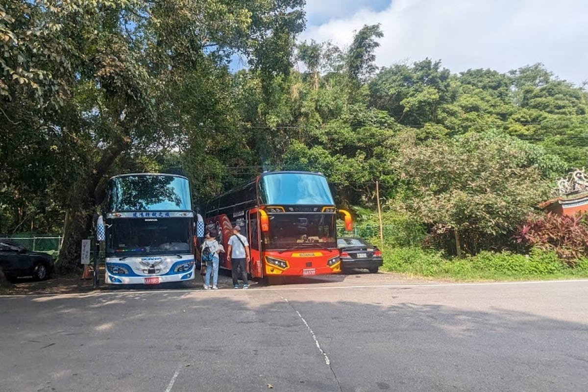 兩輛大型遊覽車停在山邊的路旁